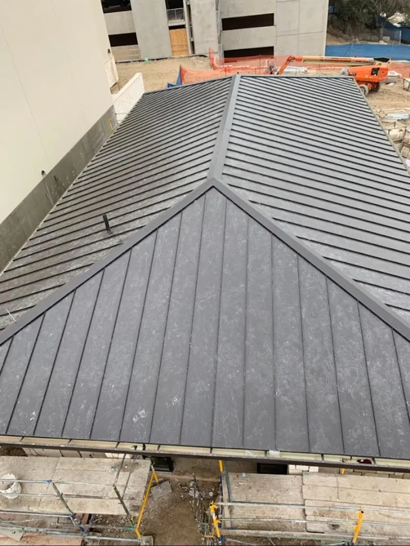 Commercial metal roof construction with crane equipment in Granbury